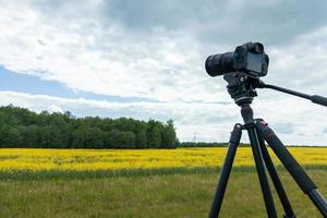 cámara sin espejo profesional moderna en trípode disparando campo amarillo en trípode, primer plano foto