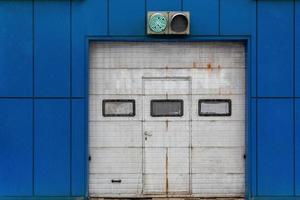 a white automatic upward sliding gate on blue garage with green lit traffic light photo