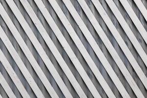 white diagonal wooden planks over gray corrugated metal sheet - flat full-frame background and texture photo