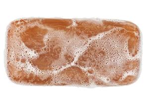 wet piece of brown tar soap isolated on white background in flat lay directly above perspective photo