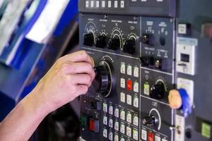 Operator hand spinning jog handle on CNC machine control panel. Close-up with selective focus and blur. photo