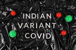 words indian variant covid laid with silver metal letters on crumpled black plastic bag background in flat lay perspective photo