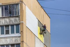 Industrial climber applying styrofoam on outside wall of apartment building photo