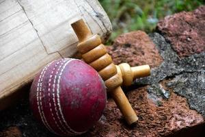 equipos deportivos de cricket en ladrillo, bate, wicket, pelota de cuero vieja, enfoque suave y selectivo. foto