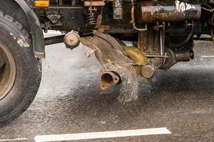 old utility truck moving on asphalt road under rainy day - close-up photo