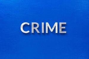 the word crime laid with silver metal characters on blue board in flat lay centered composition photo
