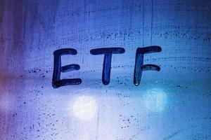 abbreviation word etf - exchange traded funds - handwritten on foggy glass window at night with neon blue back street light photo