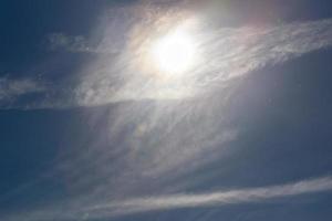 partículas de polvo en el cielo azul con nubes de sol y plumas en el día de primavera foto