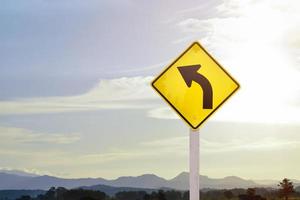 Traffic warning sign on pole, left curve means the way ahead is a right curve and should slow driving and drive carefully. photo