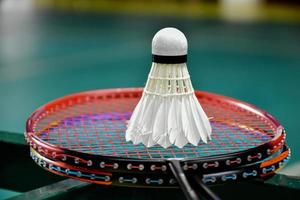 Cream white badminton shuttlecock and racket on floor in indoor badminton court, copy space, soft and selective focus on shuttlecocks. photo