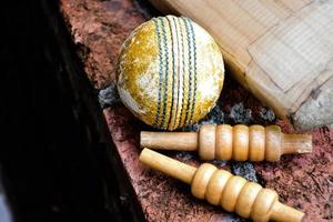 equipos deportivos de cricket en ladrillo, bate, wicket, pelota de cuero vieja, enfoque suave y selectivo. foto