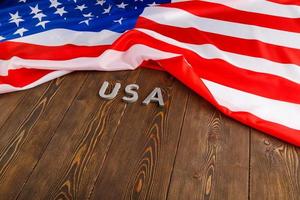 bandera de los estados unidos de américa arrugada y con la palabra usa colocada sobre un fondo de superficie de madera con textura plana foto