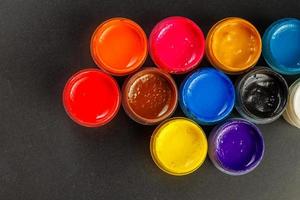 close-up background of opened small gouache paint jars on black surface photo