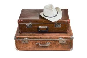 old soviet suitcases one on top of other with white summer hat isolated on white photo