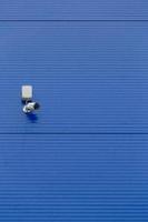pequeña cámara de seguridad blanca en una gran pared de silo de acero azul foto