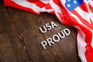 palabras usa orgullo colocadas con letras de metal plateado en una superficie de madera marrón con la bandera de los estados unidos de américa foto