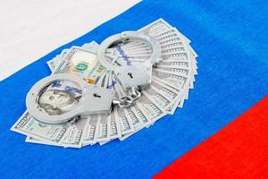 silver metal handcuffs over dollar banknotes over Russian national flag photo