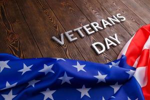 the words veterans day laid with silver metal letters on wooden board surface with crumpled usa flag photo