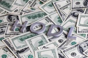 The words HODL laid with aluminium letters on dollar banknotes - with selective focus blur photo