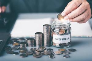 A young man put a coin in a glass jar,Finance and investment concepts, growth from profits and dividends,Investing in the stock market and trading cryptocurrencies,future income planning photo