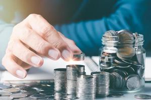 The young man put the coins on the stack of coins.Finance and investment concepts, growth from profits and dividends,Investing in the stock market and trading cryptocurrencies,future income planning photo