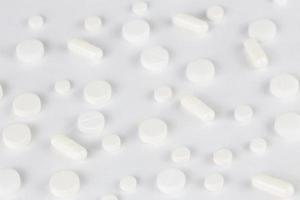 fondo de pastillas, tabletas blancas esparcidas sobre una superficie plana blanca foto