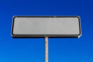 una pequeña maqueta de señal de carretera blanca sobre fondo de cielo azul foto