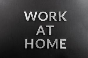 the words work at home laid with silver metal letters on matte black background in flat lay perspective photo