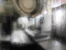 wet and dirty glass of cnc milling machine - close-up with selective focus and blur photo