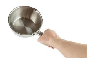 bare caucasian hand holding small shiny stainless steel pot - isolated on white photo