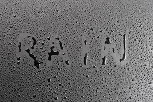 the word rain handwritten on matte black hydrophobic matte surface with water drops photo