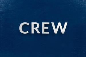 the word crew laid with brushed white metal letters over flat blue board - in center of picture photo