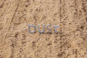 the word dust standing on dusty road surface in linear perspective photo