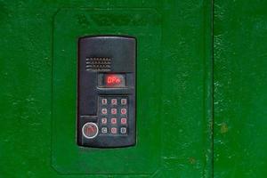 An intercom on green painted red steel surface with a keypad, digital display and rfid sensor for calling close-up photo