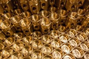 Shiny yellow metal parts background. Shiny brass metal threaded hexagonal parts after turning and machining. photo