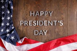 words happy presitdents day laid with real letters on wooden board near US flag photo