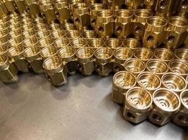 Shiny yellow metal parts background. Shiny brass metal threaded hexagonal parts after turning and machining. photo