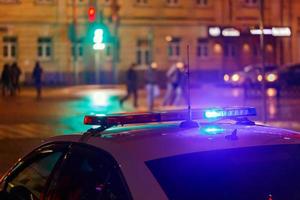luces nocturnas de coches de policía en las calles de la ciudad con peatones borrosos cruzando la calle en el fondo foto