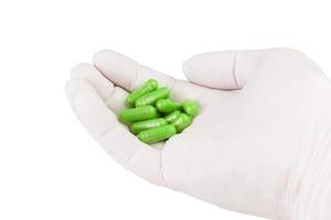 hand in medical glove holding ufo green color organic med capsules isolated on white background closeup photo