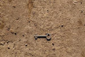 old key on dry dirt ground surface under direct sunlight photo