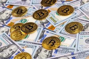 yellow bitcoin coins scattered over US dollar paper banknotes, closeup with selective focus photo