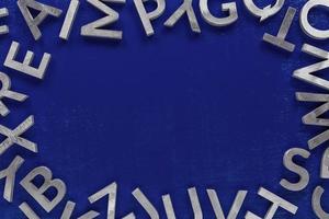 maqueta de marco hecha de caracteres del alfabeto inglés de metal plateado sobre fondo azul. foto