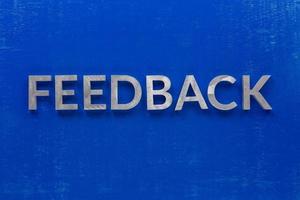 The word feedback laid on blue painted board with thick silver metal aphabet characters. photo