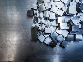 pile of small machined shiny steel cubes on metal surface photo