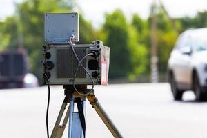 mobile speed camera device working on summer daytime road with blurry white car in background photo