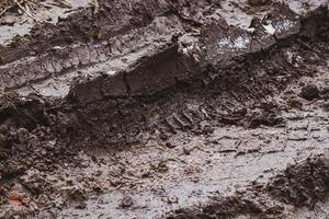textura sucia. tierra mojada y empapada después de la lluvia. superficie de barro en otoño. marcas de neumáticos en la suciedad. pista de carreras foto