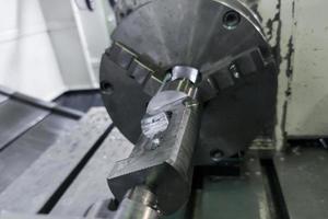 cylindrical workpiece clamped in 4-th axis of cnc milling machine after rough end milling operation photo