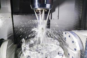 a process of industrial wet milling in 5-axis cnc machine with coolant flow under pressure and motion blur of splashes photo