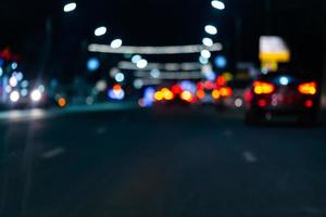 imagen desenfocada del tráfico nocturno de coches callejeros - vista desde la carretera. fondo colorido de la vida nocturna. foto