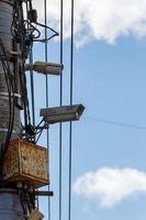 two old cctv security surveillance cameras on street light pole on blue sky background photo